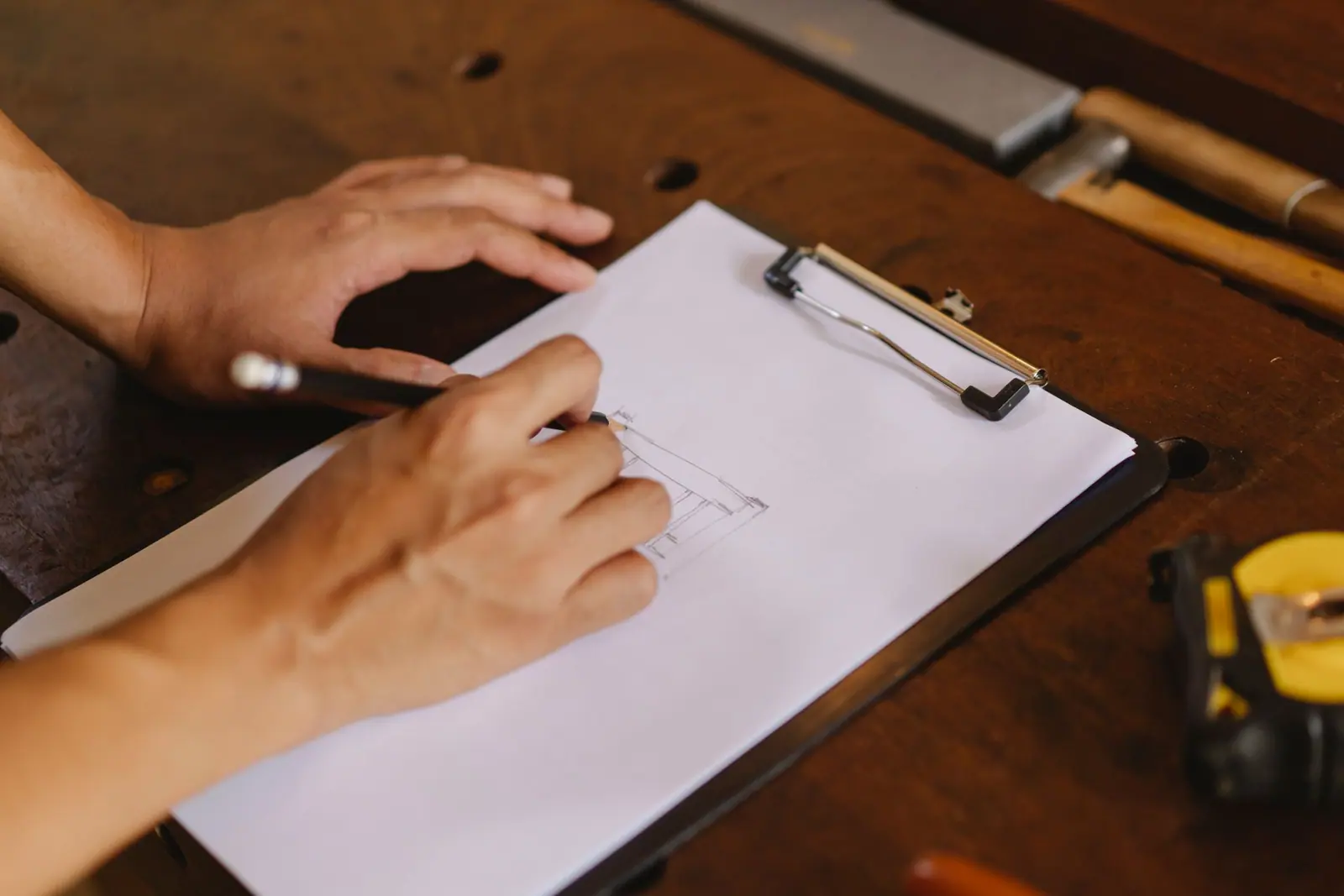 Hand writing an inventory list on paper next to a tape measure